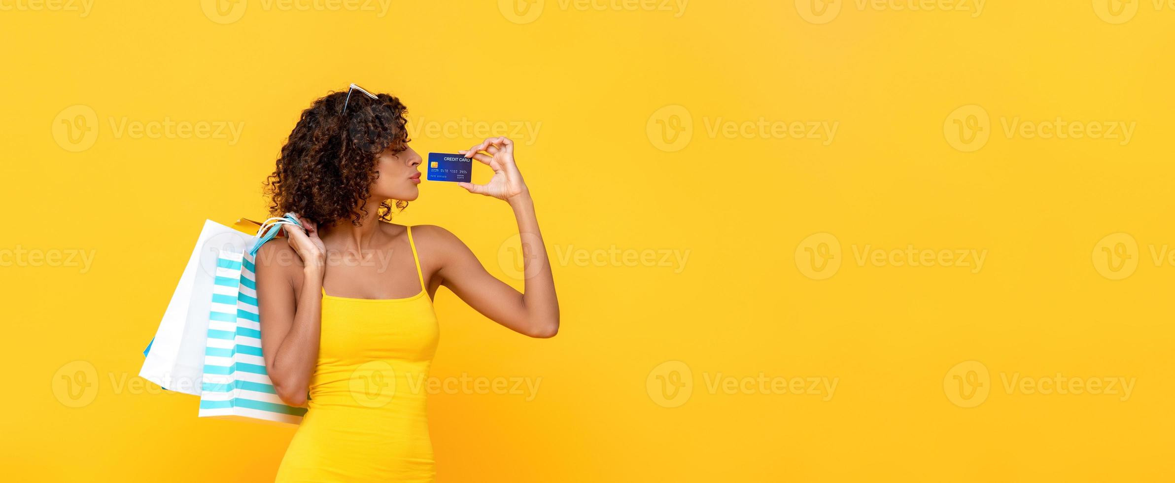 fashionabla lockigt hår kvinna som bär shoppingkassar med kreditkort på gul banner bakgrund med kopia utrymme foto