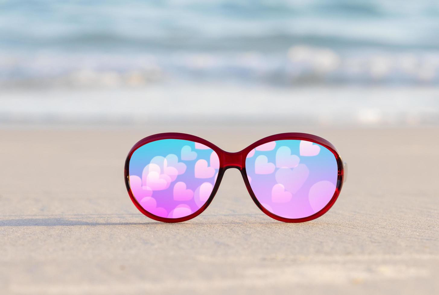 solglasögon på sand vacker sommarstrand och ett rosa hjärta för alla hjärtans dag foto