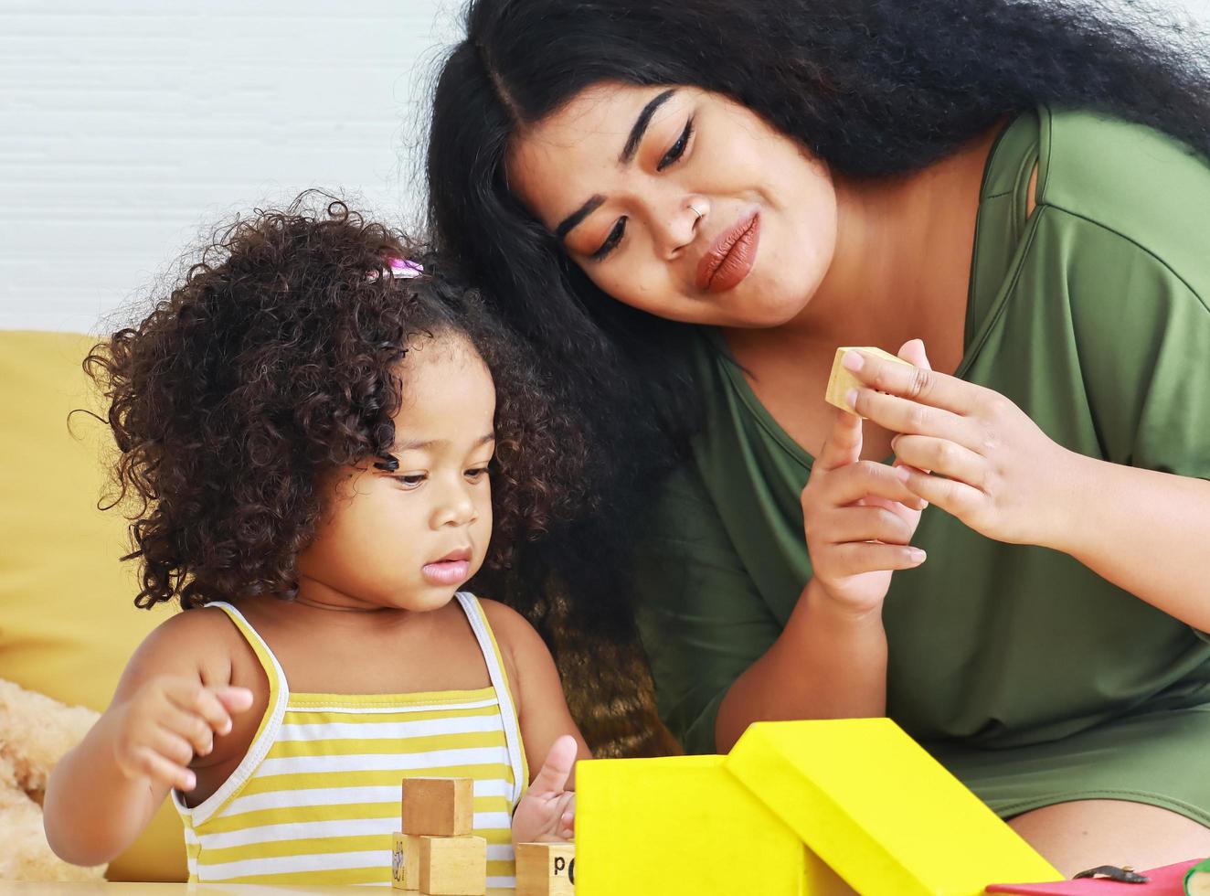 mamma har kul att leka med sin dotter på helgdagar och gula presentförpackningar lockigt hår dotter leker med sin mamma i huset. foto