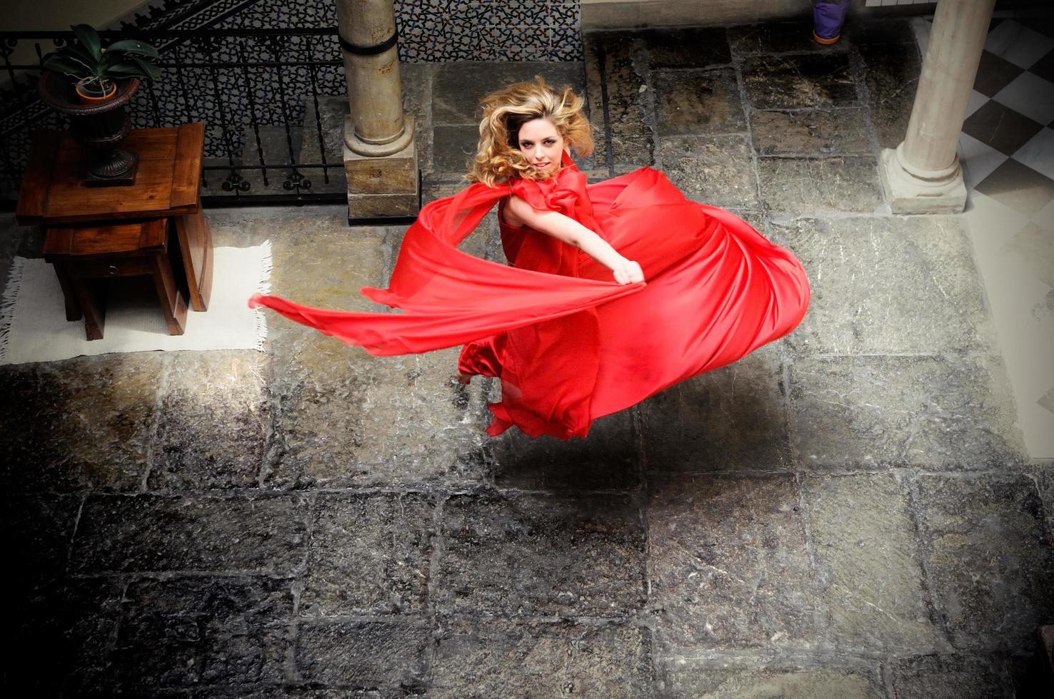 vacker blond kvinna, klädd i en röd klänning, hoppar foto
