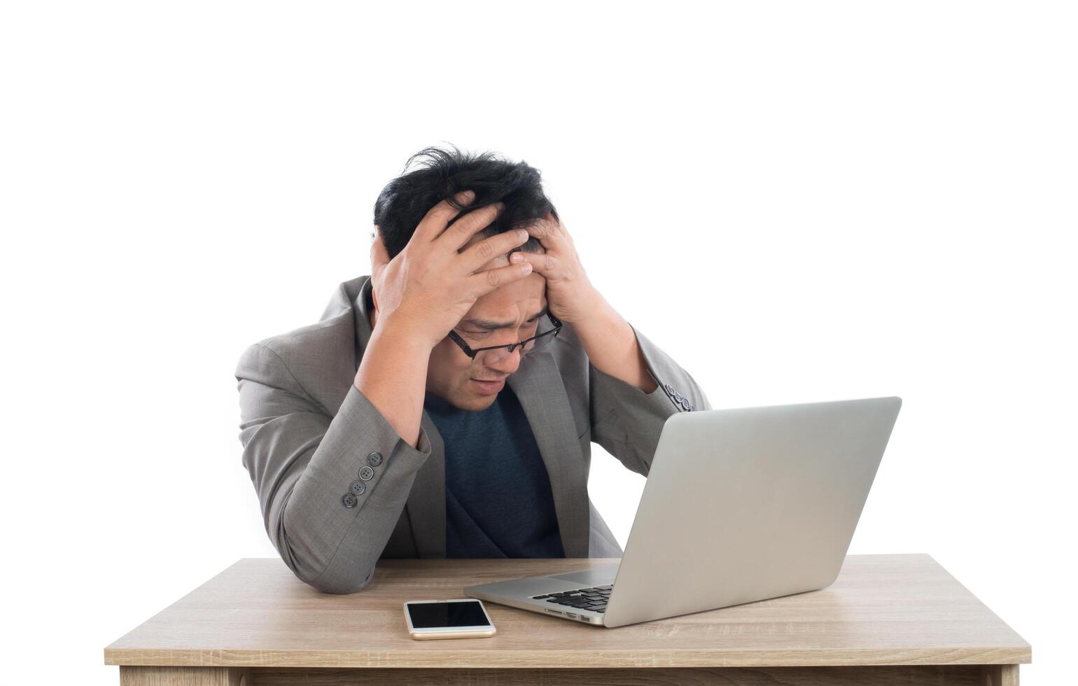 stressad affärsman arbetar med laptop sitter vid bordet isolerad på vit bakgrund. foto