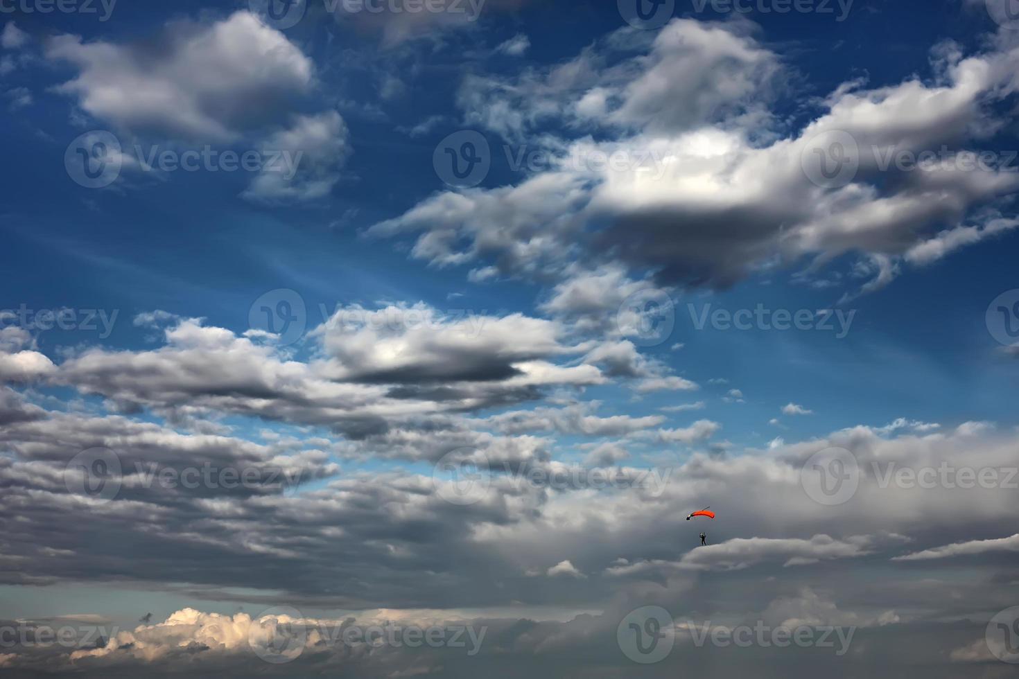 fallskärmshoppare i himlen. en ensam fallskärm bland vackra moln. fallskärmshoppare på färgglad fallskärm i solig solnedgång soluppgångshimlen. aktiva hobbyer foto