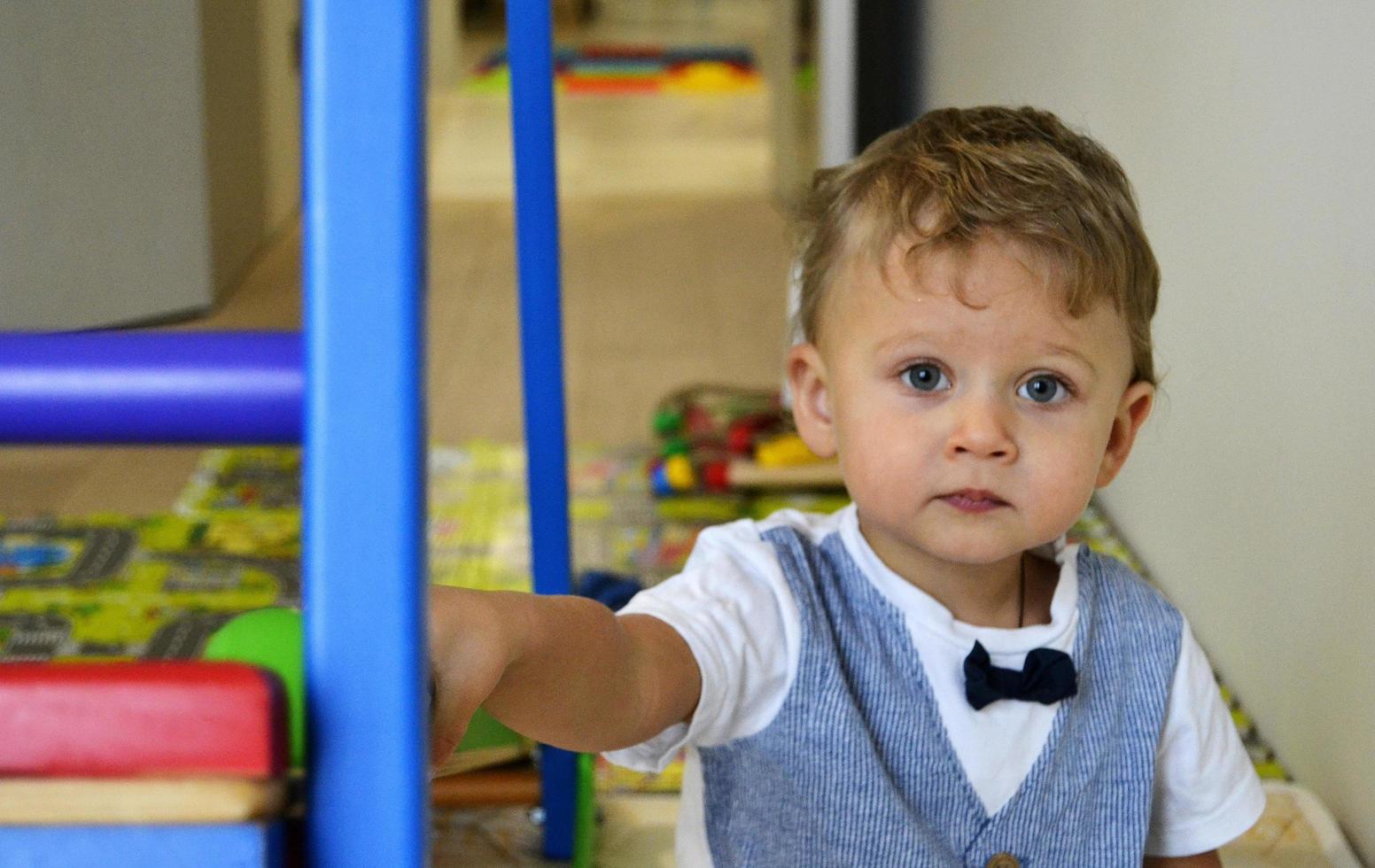 vacker baby pojke med barn ansikte poserar fotograf foto