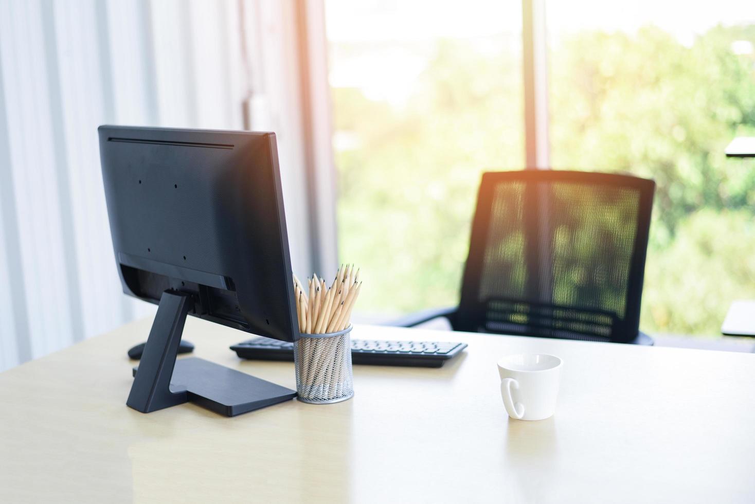 skrivbord på kontoret med datorskrivbordspennor och kaffekopp för designerskrivbord - bord arbetsplats affärskontor naturbakgrund foto