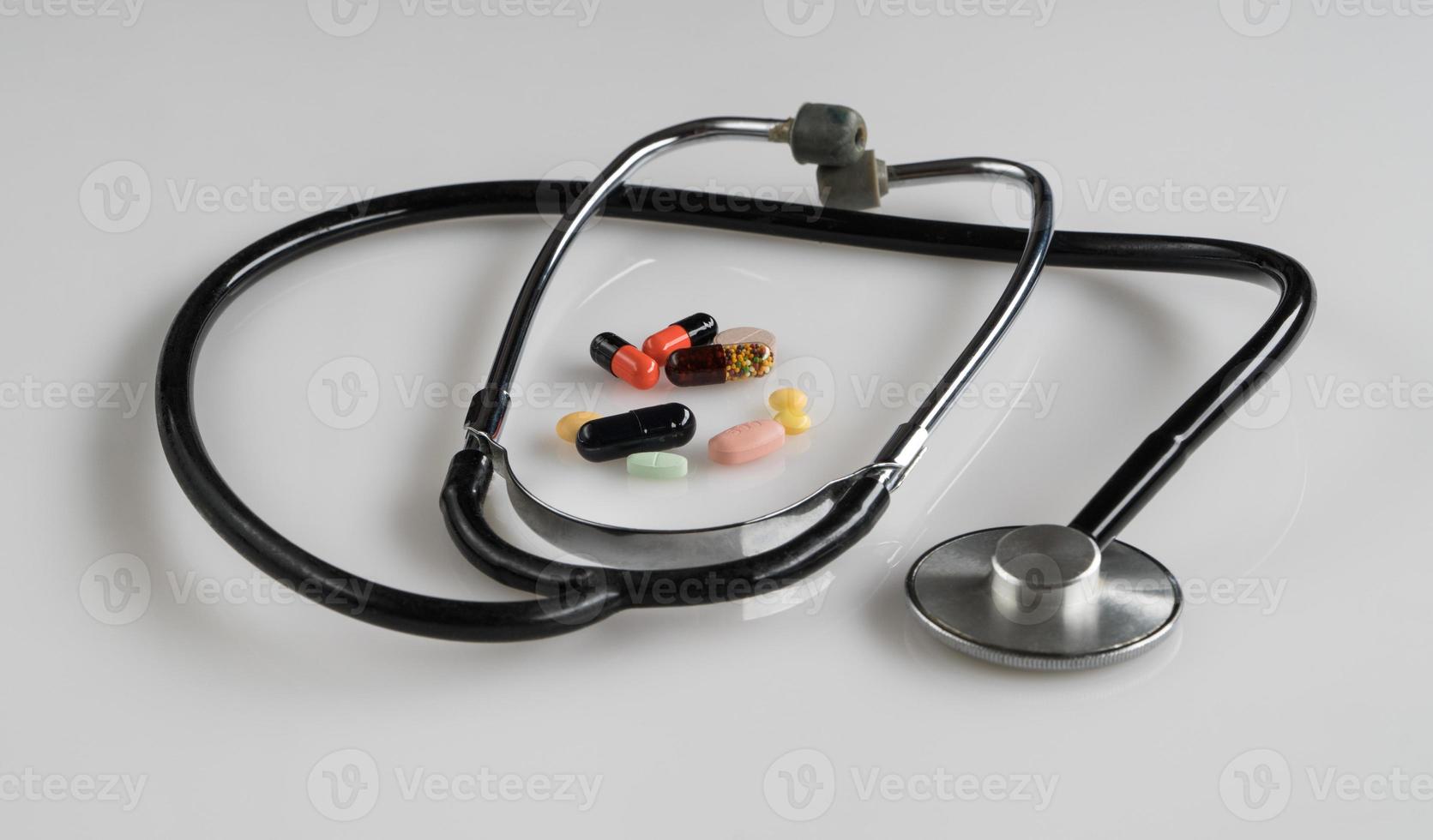 medicinskt stetoskop med piller på vit bakgrund, isolerade foto
