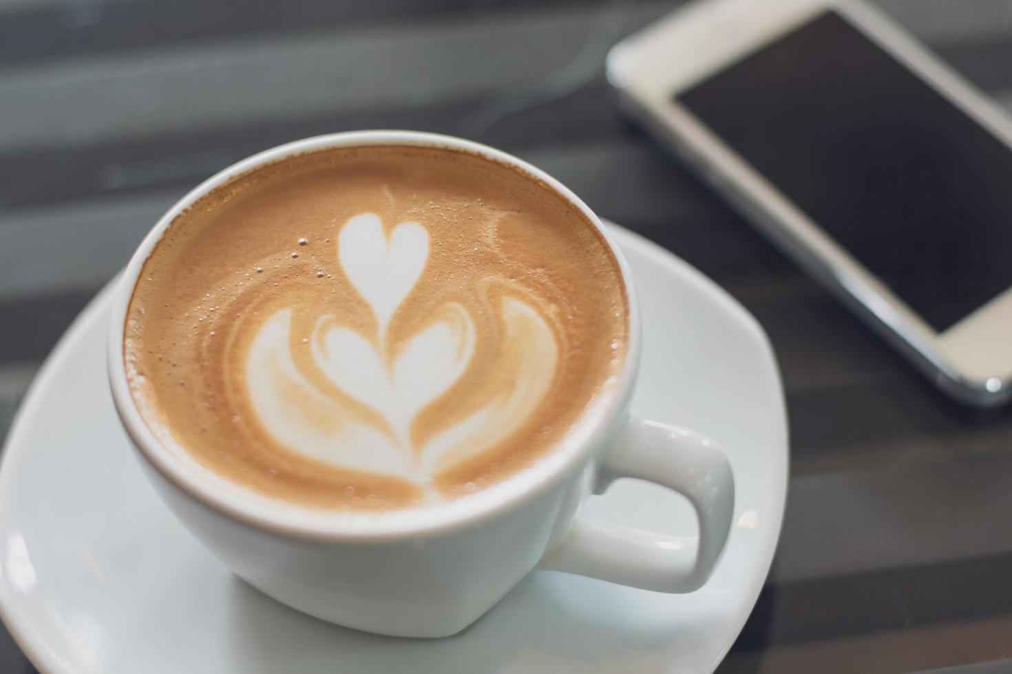 en kopp varmt latte art kaffe på träbord foto