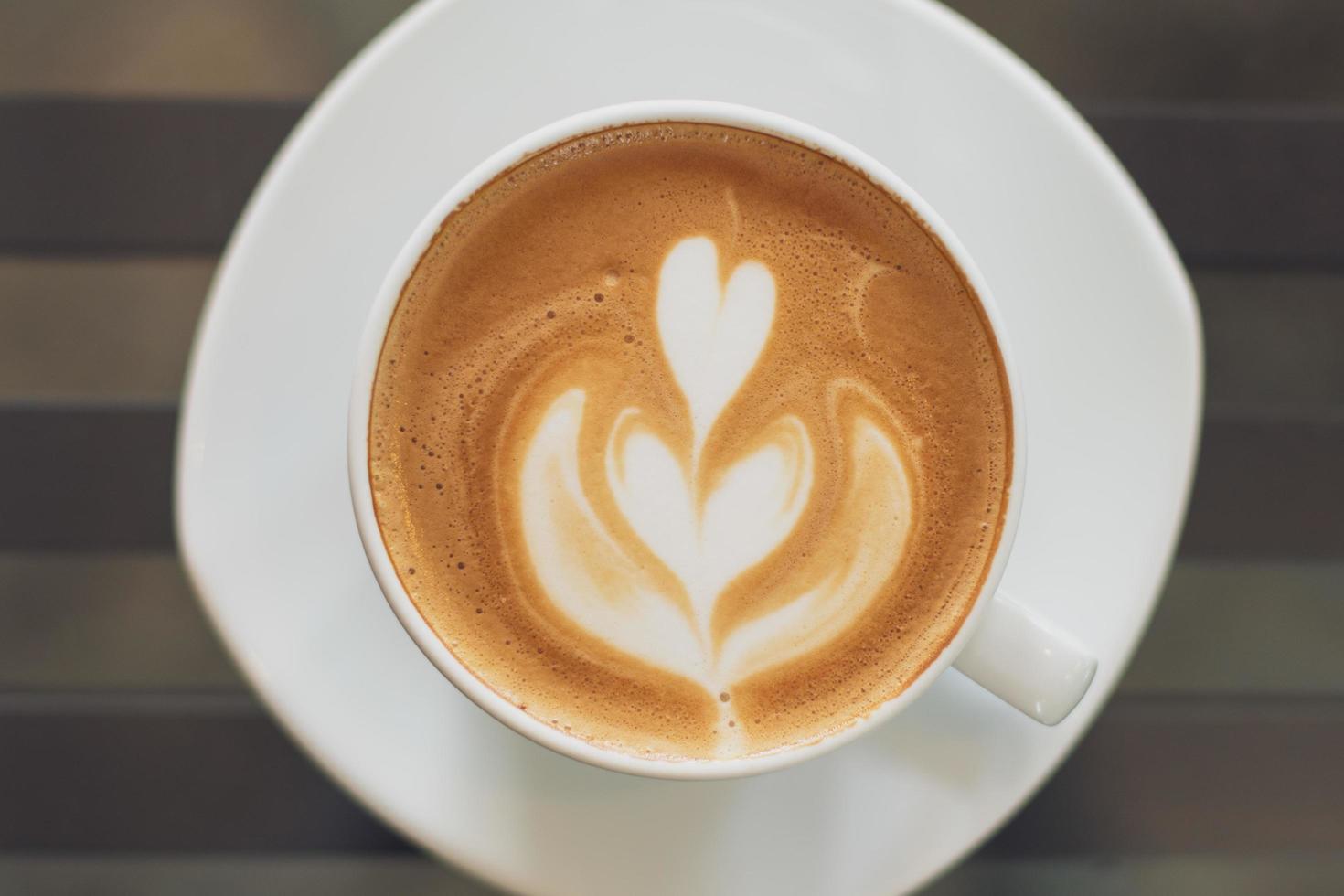 en kopp varmt latte art kaffe på träbord foto