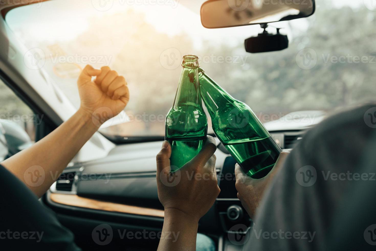 två manliga vänner firar i bilen medan de klirrar ölflaska tillsammans. foto