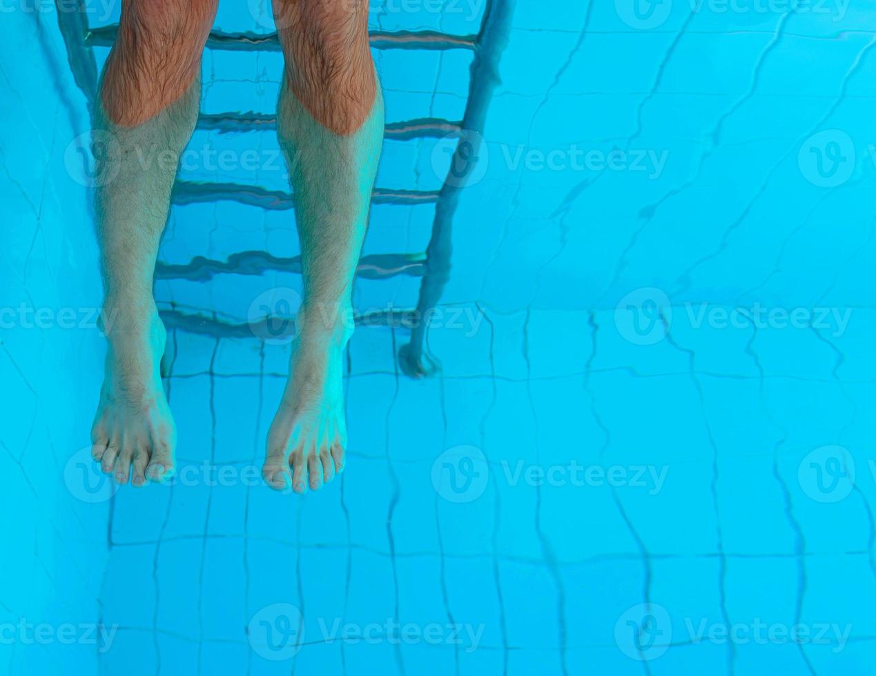 kaukasisk simning person ben och trappor i poolen under vattnet. abstrakt. fest. sommar. semester och sport koncept. foto