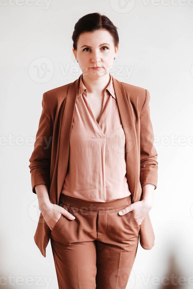 kvinna klädd i en brun kostym på en vit bakgrund. kopia, tomt utrymme foto