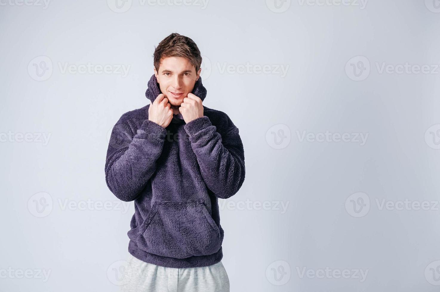 porträtt av en ung man i lila tröja med huva på en vit bakgrund. kopiera, tomt utrymme för text foto