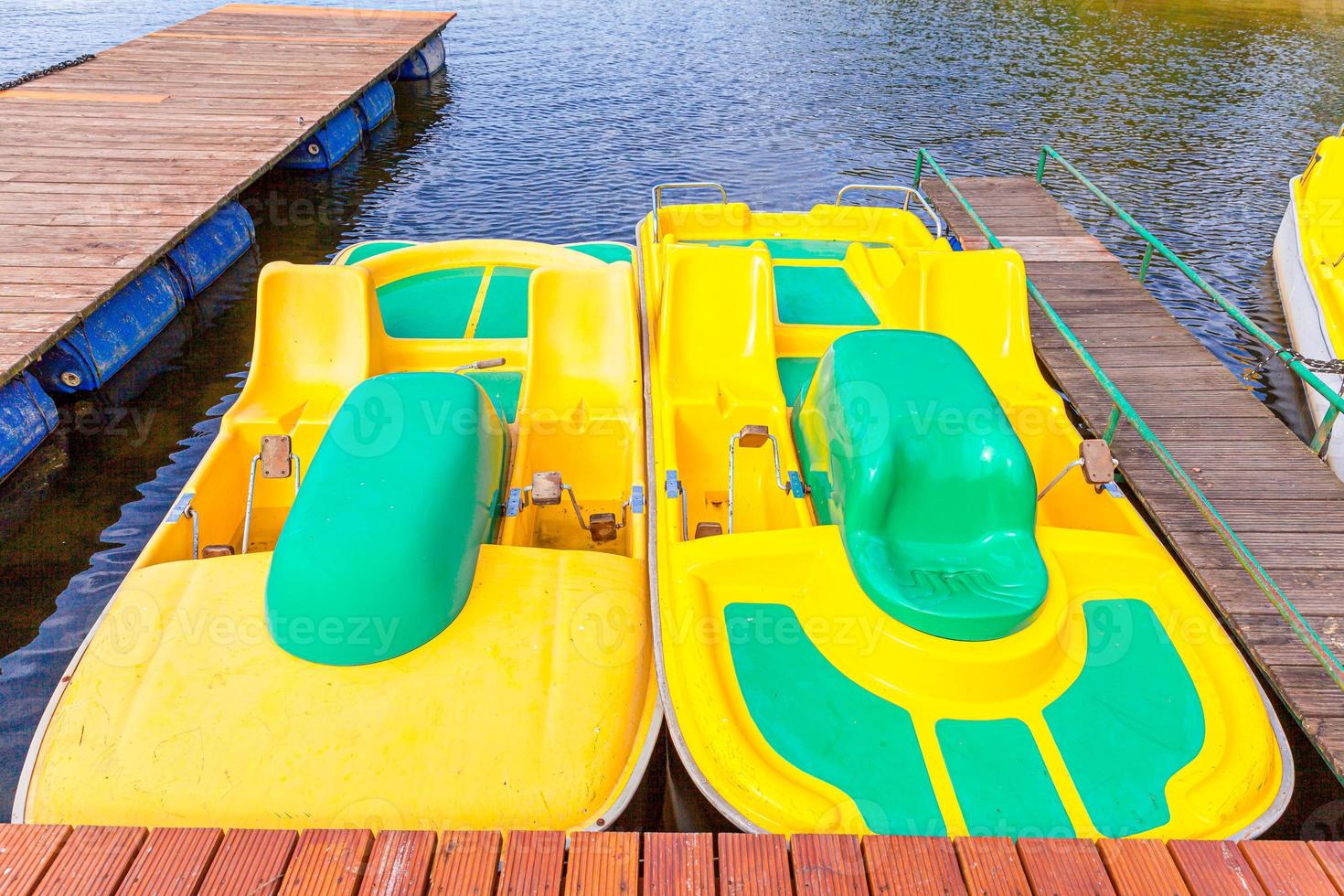 trampbåtar eller paddelbåtar katamaranstation. gula vattencyklar låsta vid sjön marina docka piren på solig sommardag. sommar fritidsaktivitet utomhus. foto