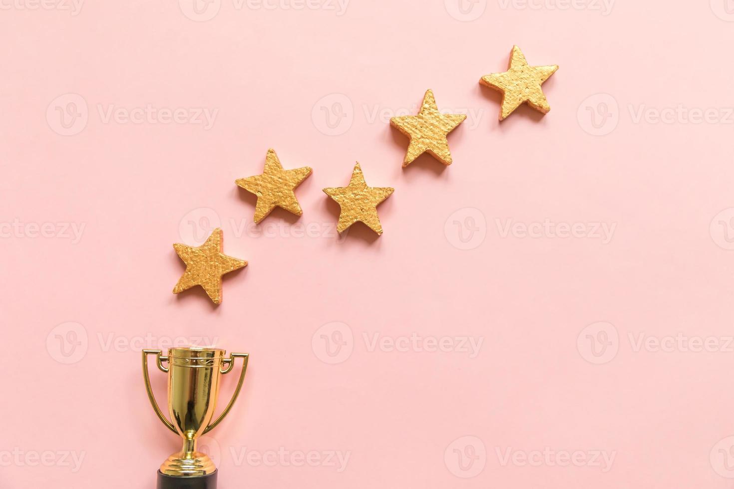helt enkelt platt lay design vinnare eller mästare guld trofé cup och 5 stjärnor betyg isolerad på rosa pastell bakgrund. seger första tävlingsplatsen. vinnande eller framgångskoncept. ovanifrån, kopieringsutrymme foto