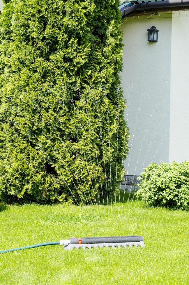 bevattningssystem, sprinkler spaying vatten över grönt gräs gräsmatta foto