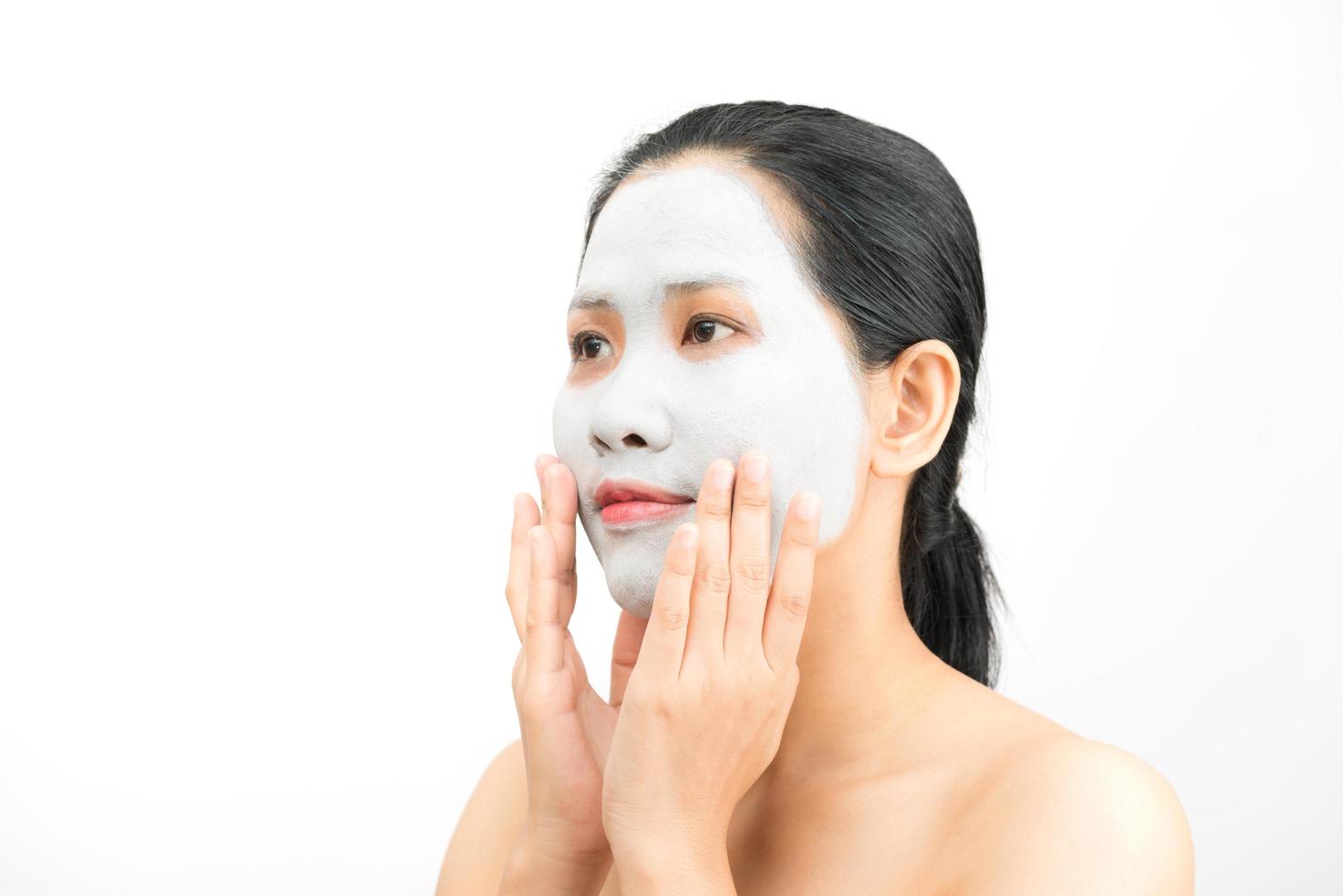 ung kvinna leransiktsmask som skalar naturligt med renande mask i ansiktet på vit bakgrund foto