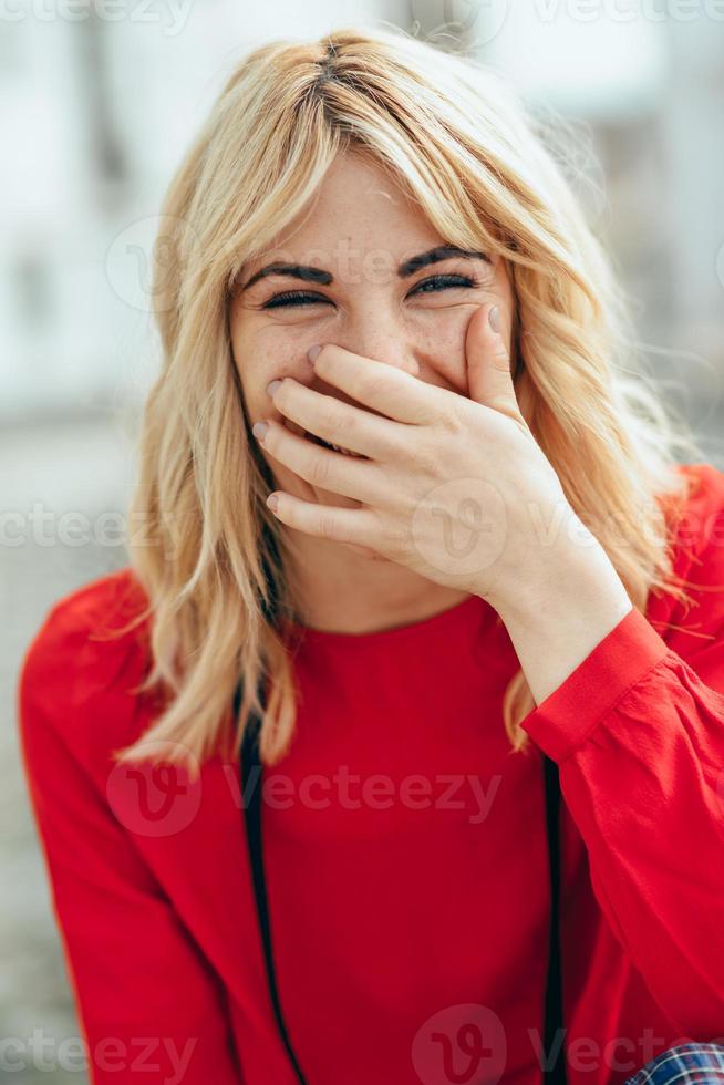 leende blond flicka med röd skjorta njuter av livet utomhus. foto