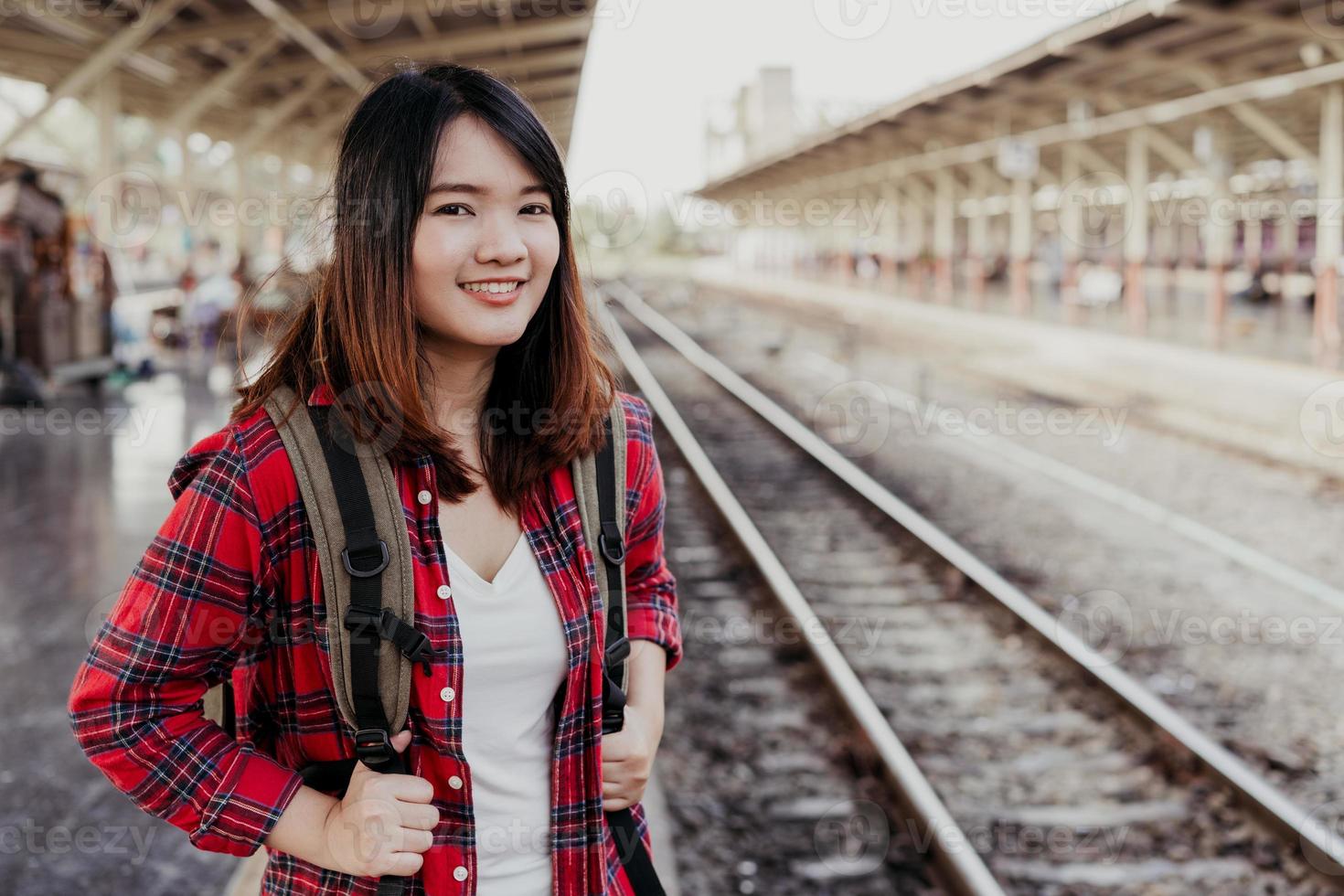 ung asiatisk kvinna backpacker resenär gå ensam på tågstationen plattform med ryggsäck. asiatisk kvinna väntar tåg på tågstationen för resor. sommar semester resor eller unga turist koncept. foto