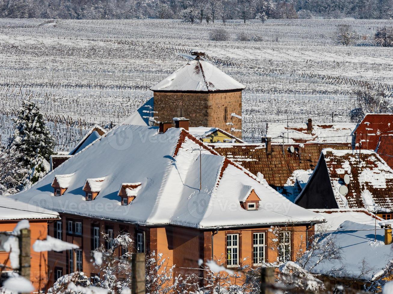 en gammal Alsace stad under snön. katedralens klocktorn och taken på medeltida hus. foto