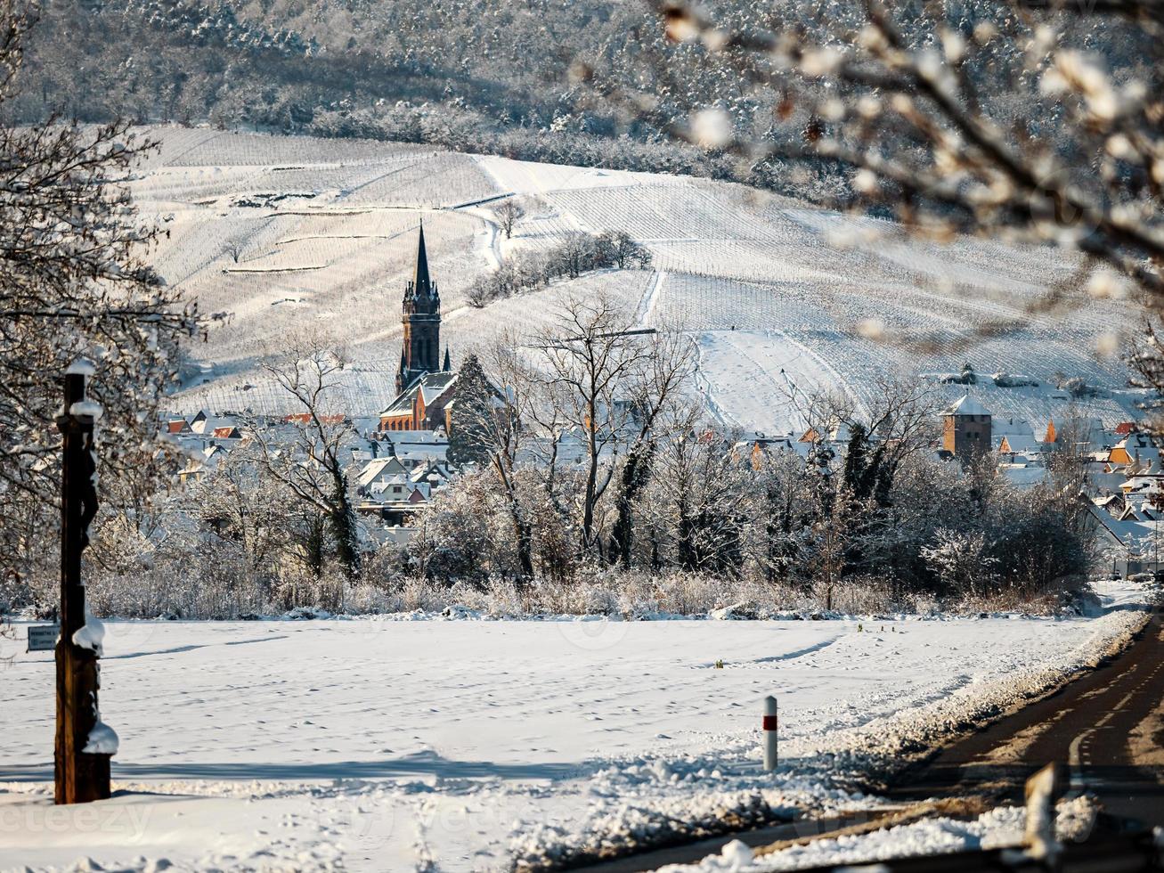 en gammal Alsace stad under snön. katedralens klocktorn och taken på medeltida hus. foto