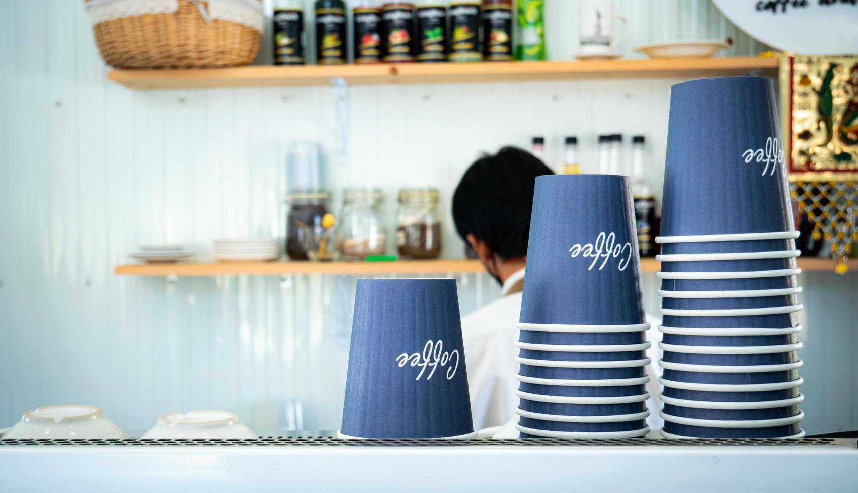 pappersmuggar eller plastmuggar för kaffe engångsbruk staplade upp och ner på kaffemaskinen i caféet foto