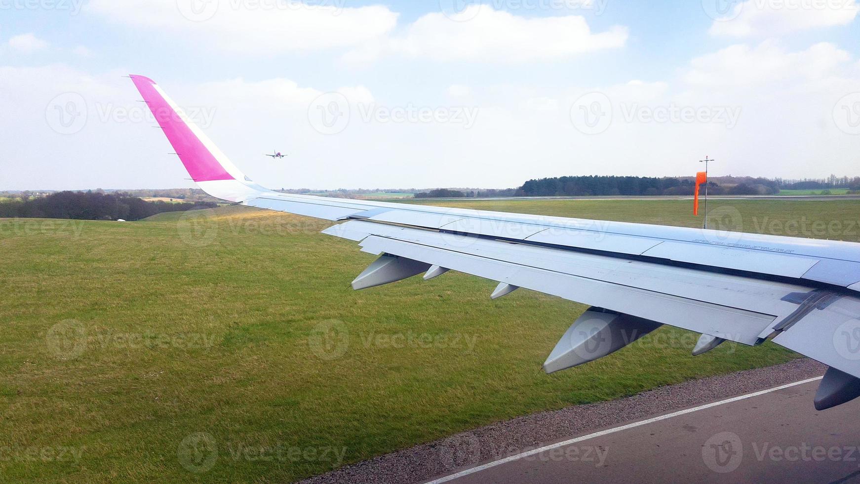 Wizzair-plan närmar sig banan medan ett annat plan landar. foto