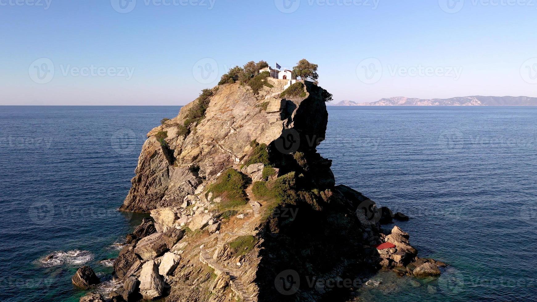 flygdrönare utsikt över pittoreska kapellet av Saint John byggt på den berömda från mama mia filmklippan, ön Skopelos, sporaderna, Grekland. solnedgångsskott. foto