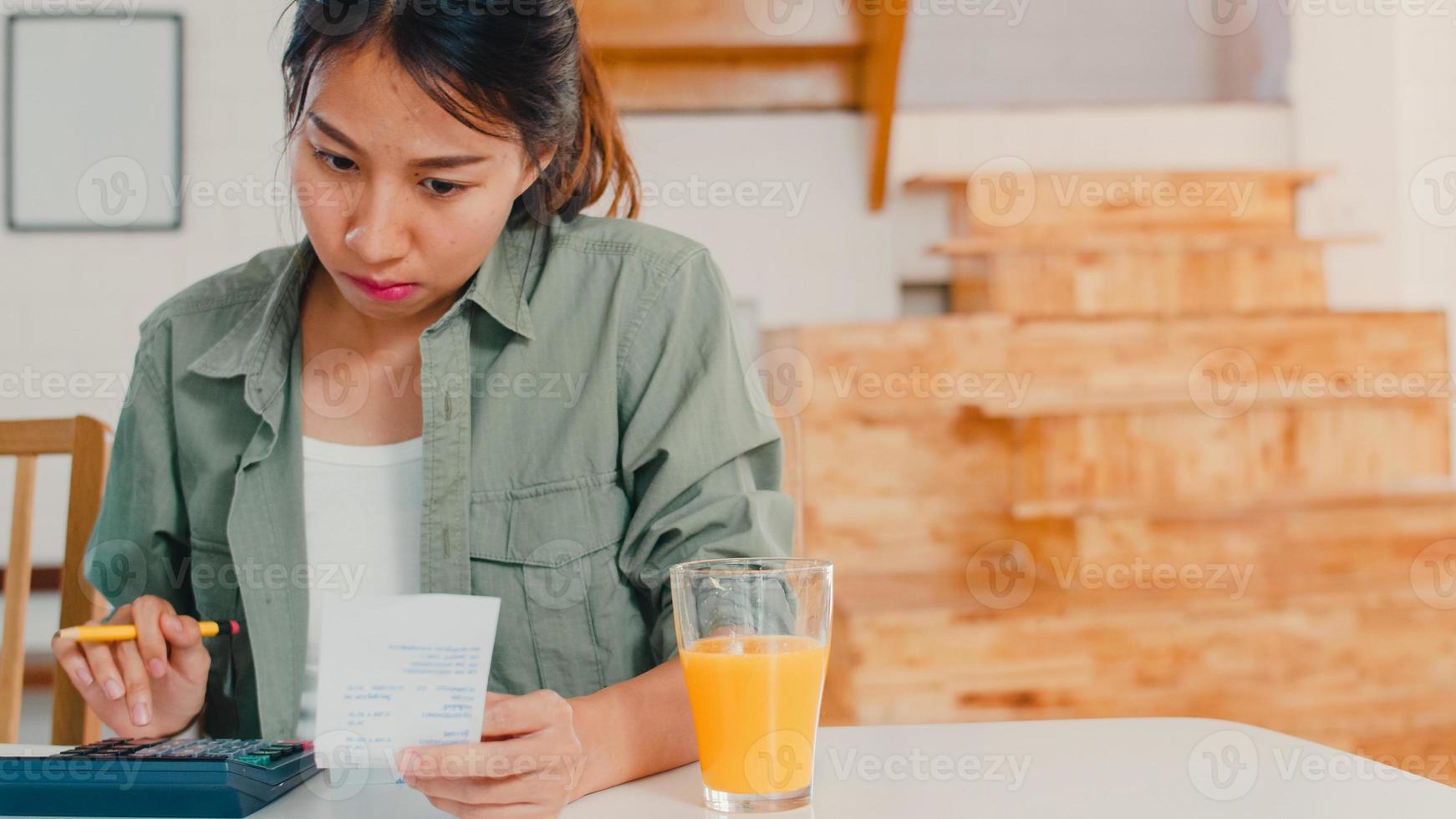 affärsasiatiska kvinnor register över inkomster och utgifter hemma, ung asiatisk flicka orolig, allvarlig, stress medan du använder laptop rekord budget, skatt, finansiellt dokument som arbetar i kök koncept. foto