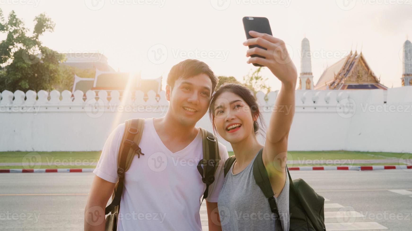 Asiatiskt bloggarpar reser i bangkok, thailand, söta par som använder mobiltelefonselfie och fotovy medan de tillbringar söt tid på semesterresan i solnedgången. par resor i staden koncept. foto