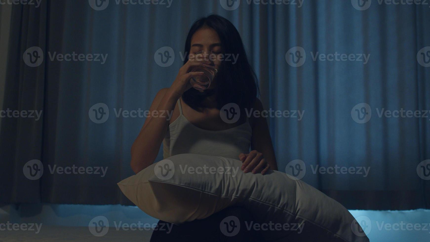 vacker asiatisk ung kvinna som sitter på sängen ta sömntabletter eller nattmedicin i sovrummet. ohälsosam sjuk indisk kvinna lider av sömnlöshet eller huvudvärk, deprimerad flicka har antidepressiva mediciner. foto