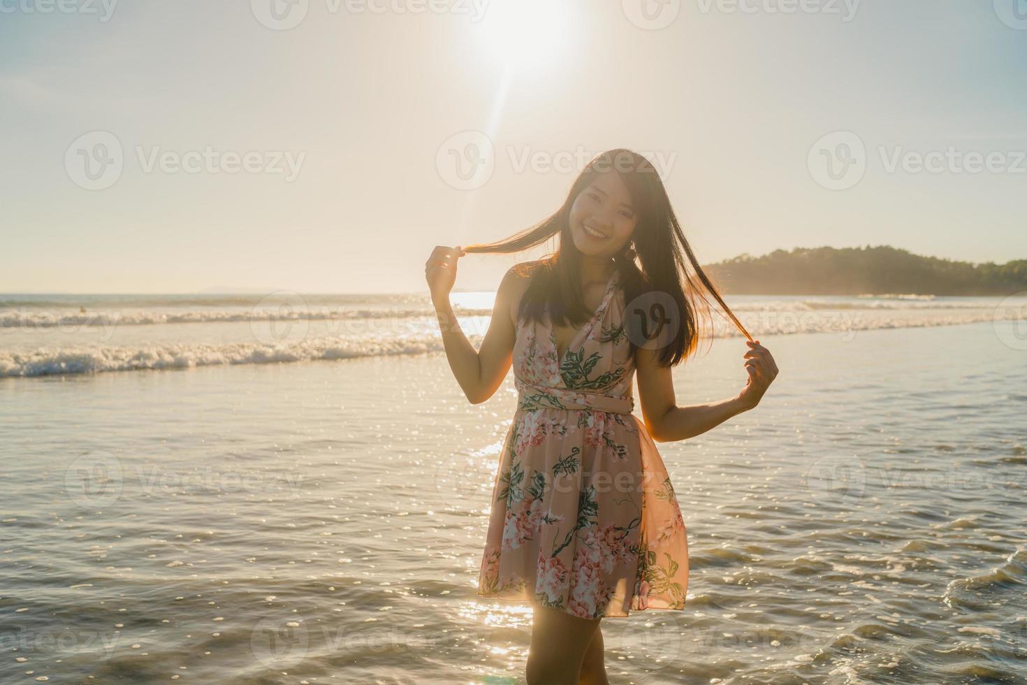 ung asiatisk kvinna känner sig glad på stranden, vacker kvinna glad slappna av leende roligt på stranden nära havet när solnedgången på kvällen. livsstil kvinnor reser på stranden koncept. foto