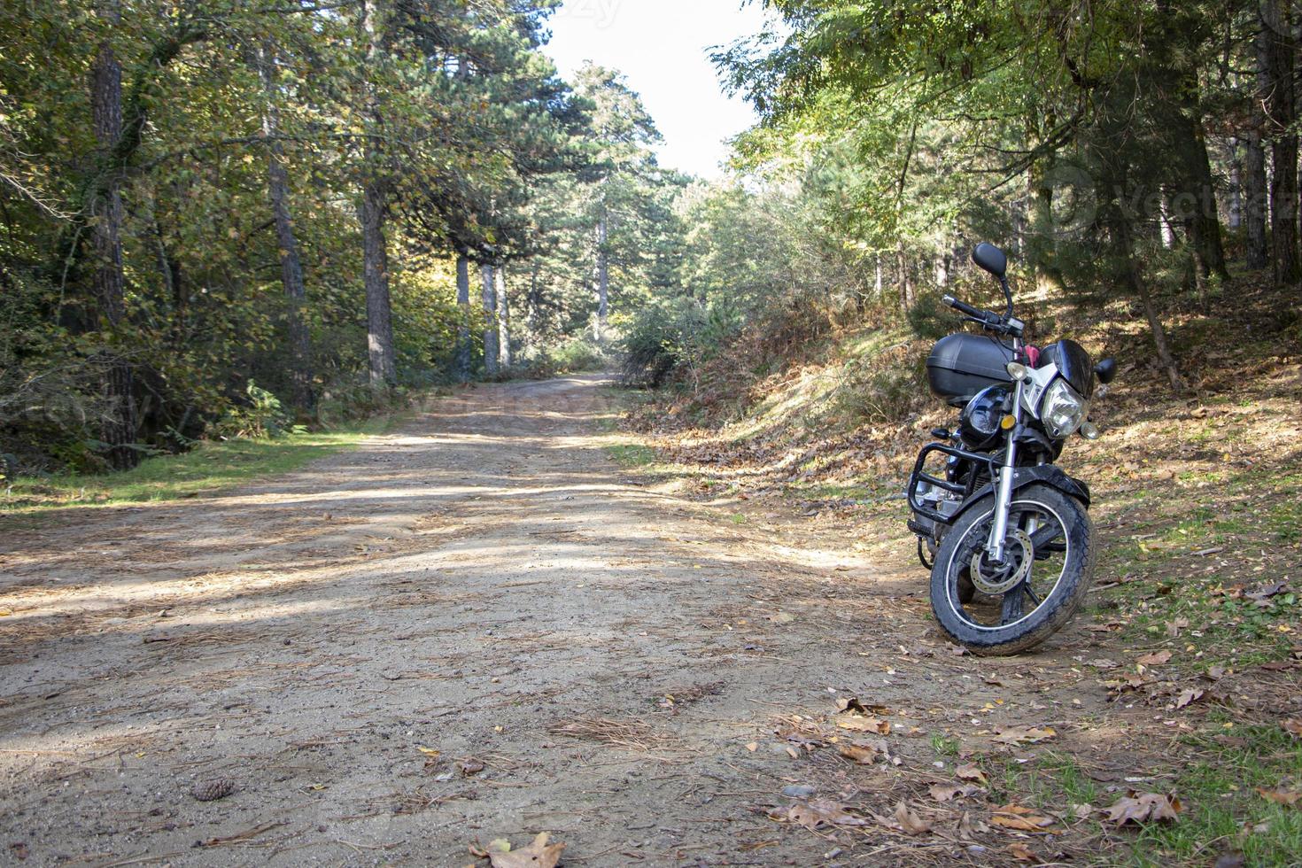 motorcykel ensam på vägen. turnera i skogen. motorcykel på skogsvägen. motorcykel i naturparkering på en stig. foto