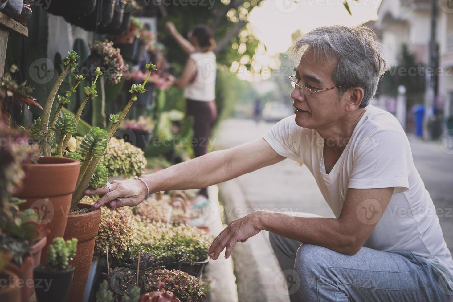 asiatisk senior man tar hand om växten hemma trädgård foto