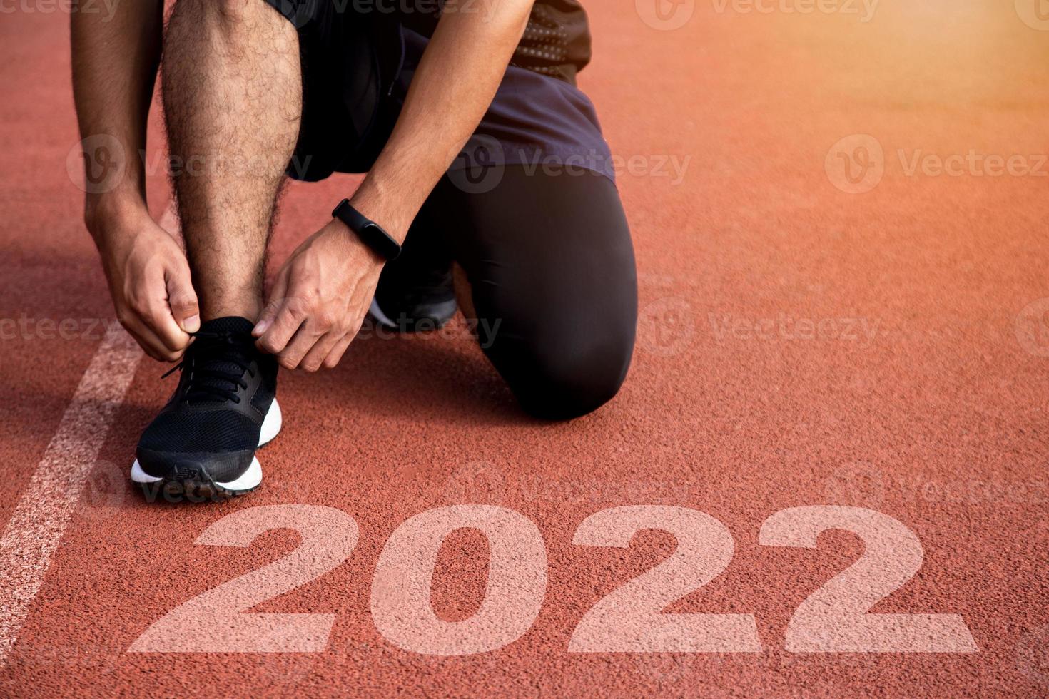 sportig man som väntar vid startlinjen för att starta det nya året 2022 med solnedgångsljus. nya mål, planer och visioner. foto