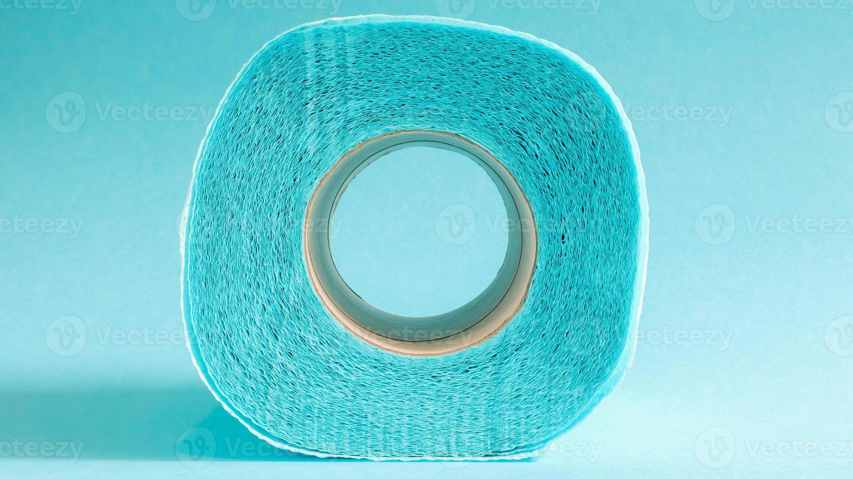 blå rulle av modernt toalettpapper på en blå bakgrund. en pappersprodukt på en kartonghylsa, använd för sanitära ändamål av cellulosa med utskärningar för enkel rivning. präglad ritning foto