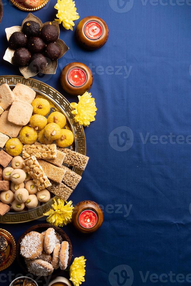 traditionella indiska sötsaker på blå bakgrund med ljus och blommor platt låg foto