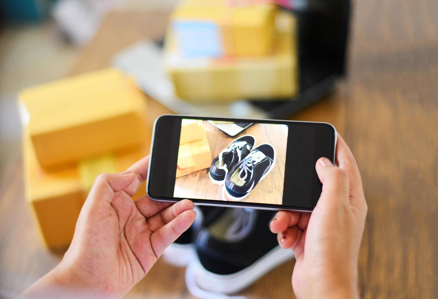 ung kvinna som tar fotosneakers med kamerasmartphone för post för att sälja online på internetmarknaden webbplats som säljer online e-handel frakt online shopping leverans och beställning foto