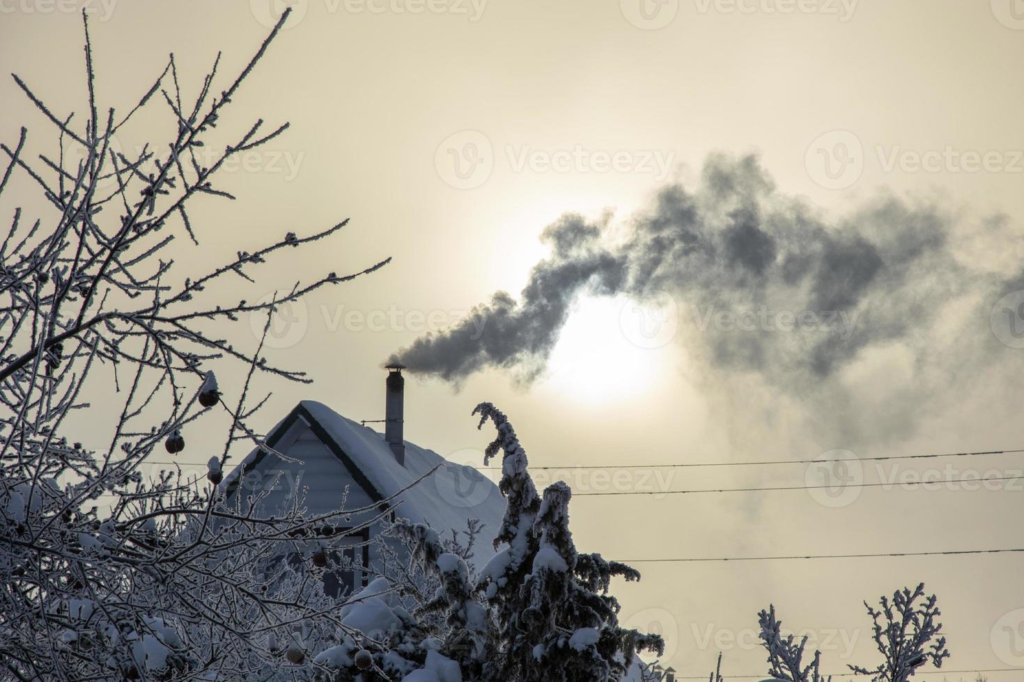 rök från skorstenen på husets tak. huset är uppvärmt på vintern. uppvärmningssäsong. foto