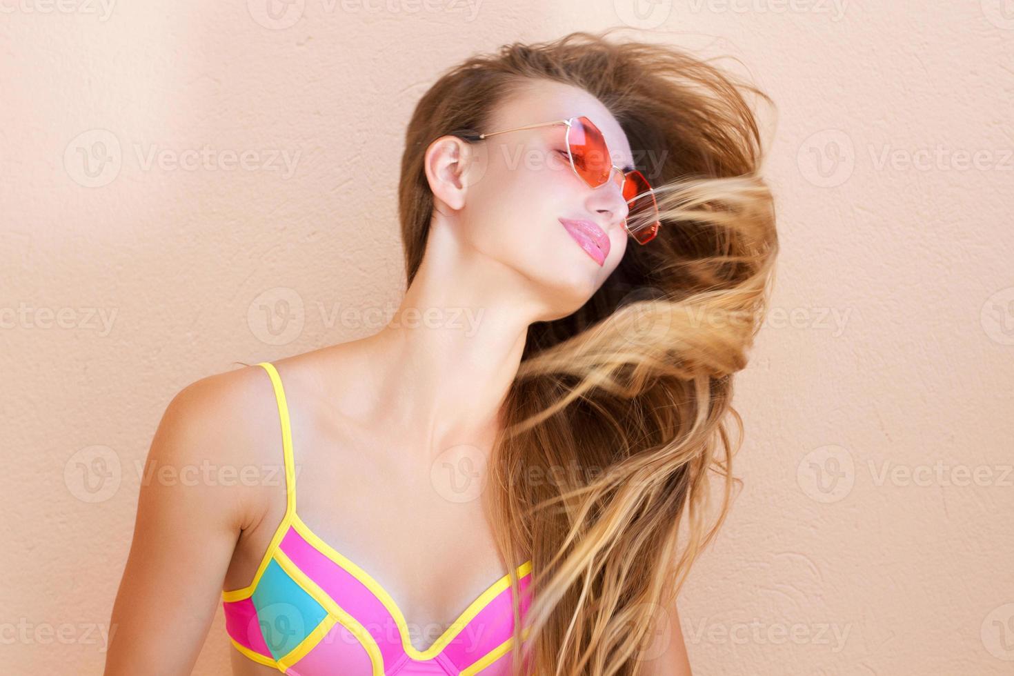 närbild av glad tjej i rosa solglasögon isolerade. sommarlov och rolig helg. sommartid koncept. leende ung kvinna i mode baddräkt. selektiv fokusering. strand sommar outfit stil. foto