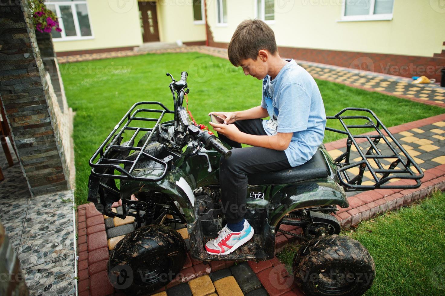 pojke i fyrhjuling atv fyrhjuling med mobiltelefon. foto