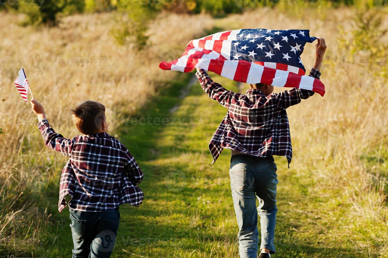 två bröder som springer med USA-flaggan. amerika semester. stolt över att vara landets barn. foto