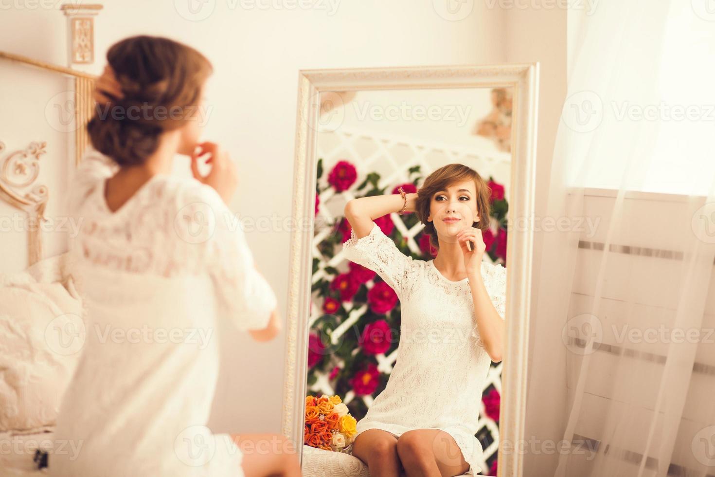 ung kvinna tittar på sig själv i spegeln foto
