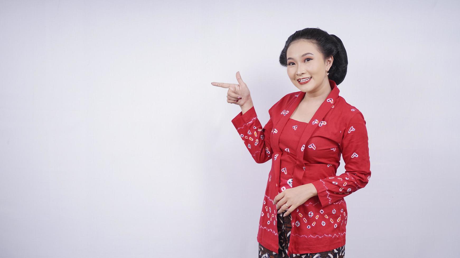 asiatisk skönhet i kebaya pekar tom sida isolerad på vit bakgrund foto