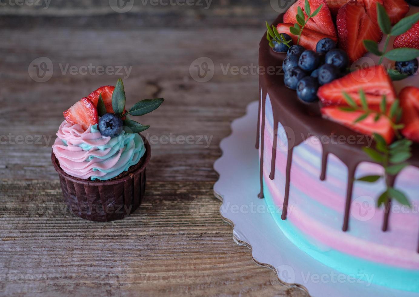 hemgjorda cupcakes med rosa och turkos grädde, dekorerade med jordgubbar och blåbär foto