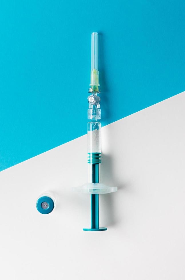 spruta med medicinsk flaska för injektion på blå och vit bakgrund. toppvy. foto