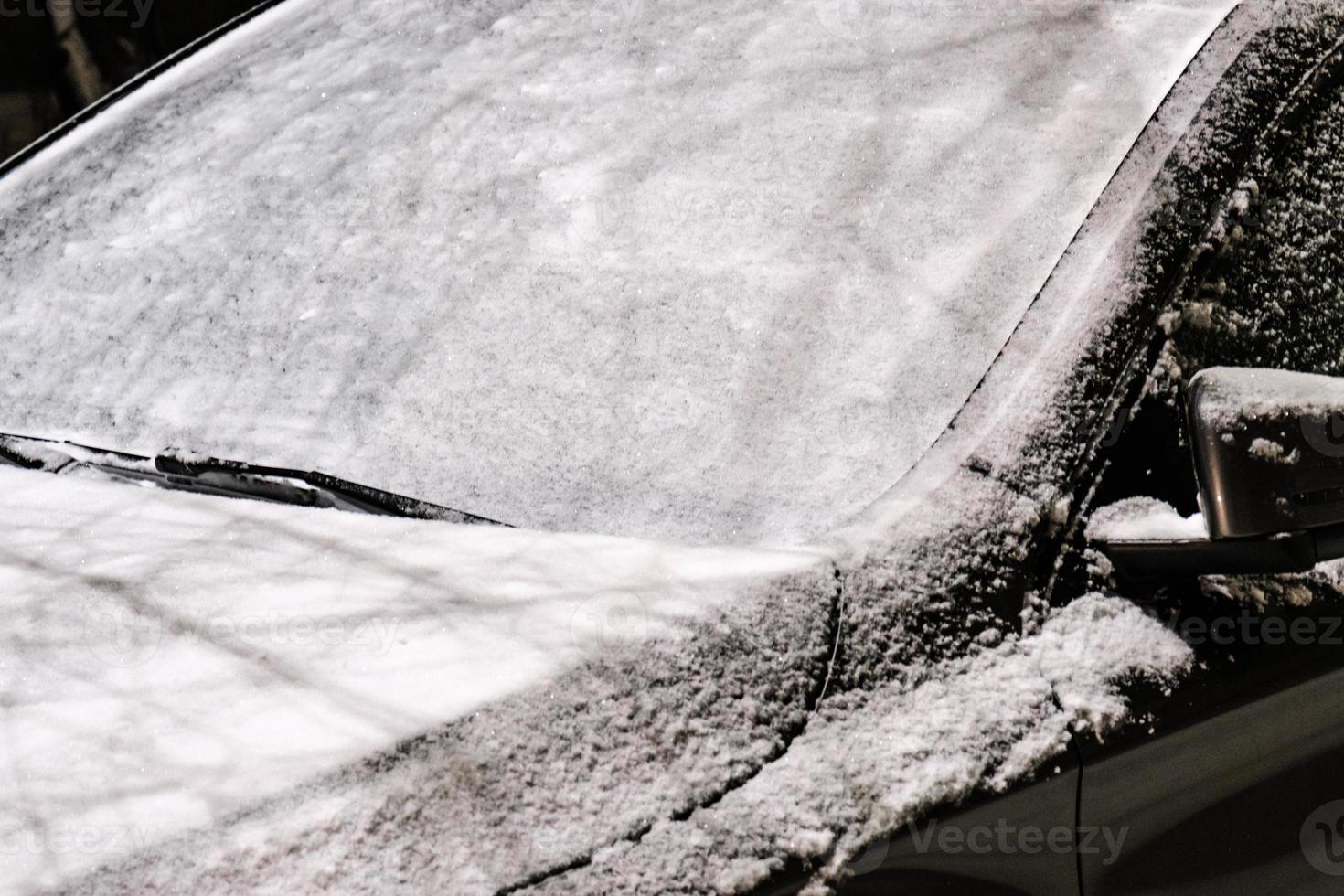 bilvindrutan täckt med ett tjockt lager av snö efter storm utanför foto
