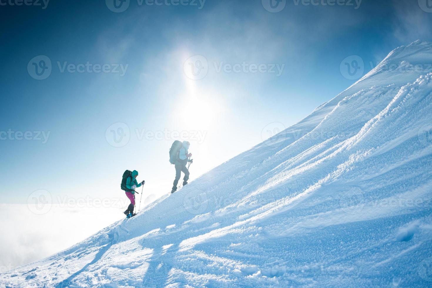 klättrare klättrar till toppen av berget på vintern foto