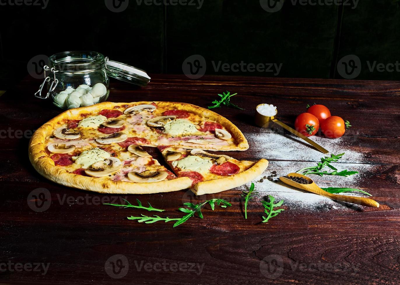 italiensk snabbmat. utsökt varm pizza skivad och serverad på träfat med ingredienser, närbild. menybild. foto