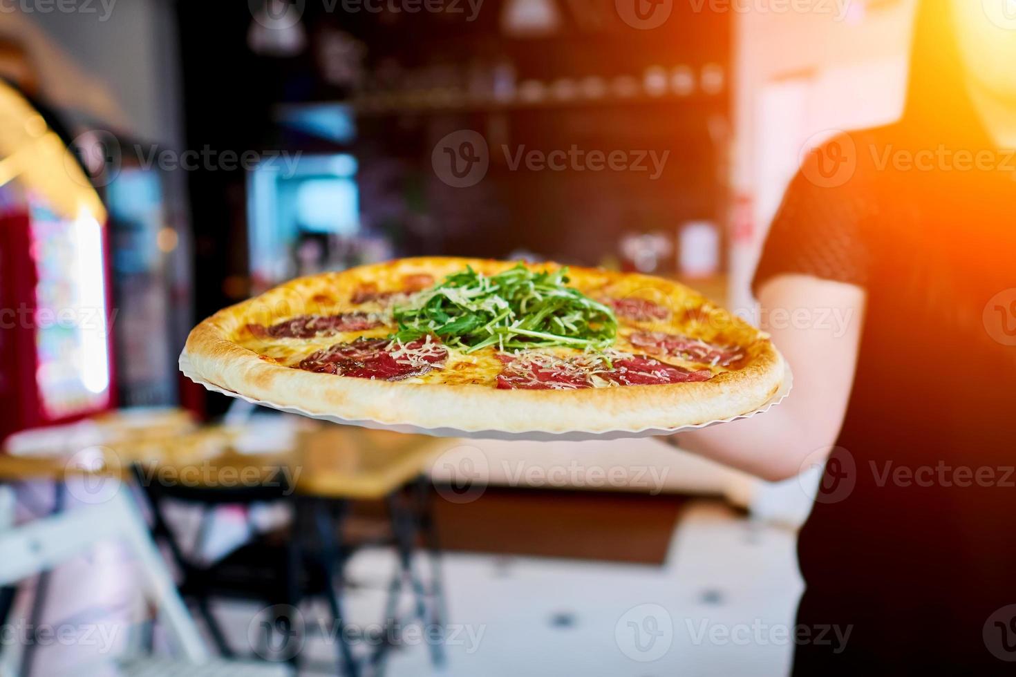 servitören bär pizzan till klienten foto