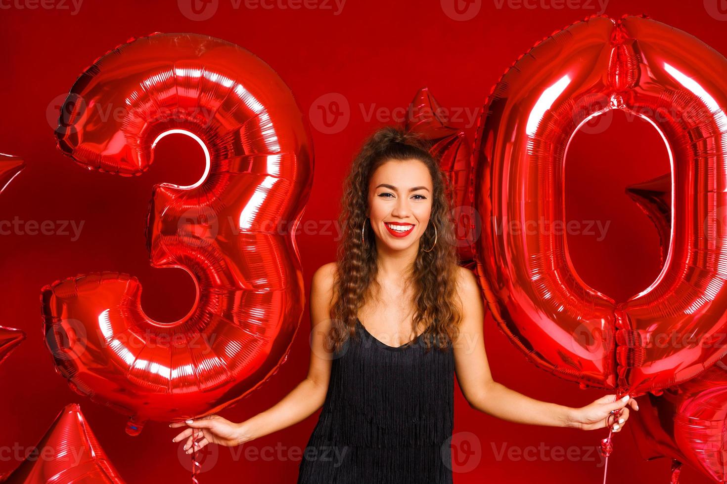 ung vuxen kvinna på bakgrunden av röda ballonger foto