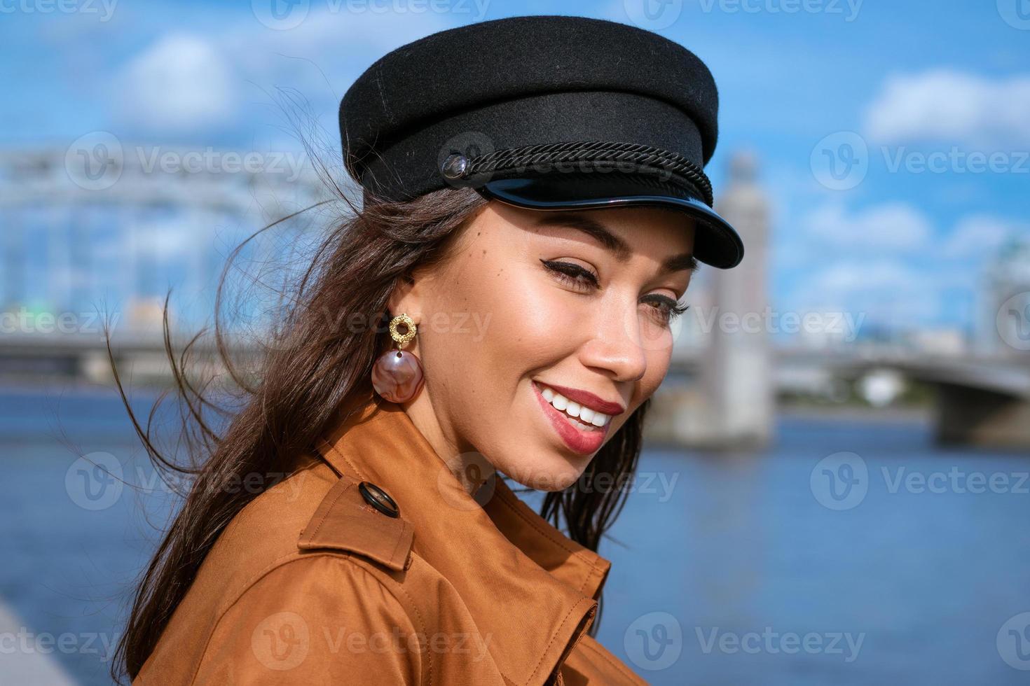 porträtt av en glad kvinna på vallen av floden i en mössa foto
